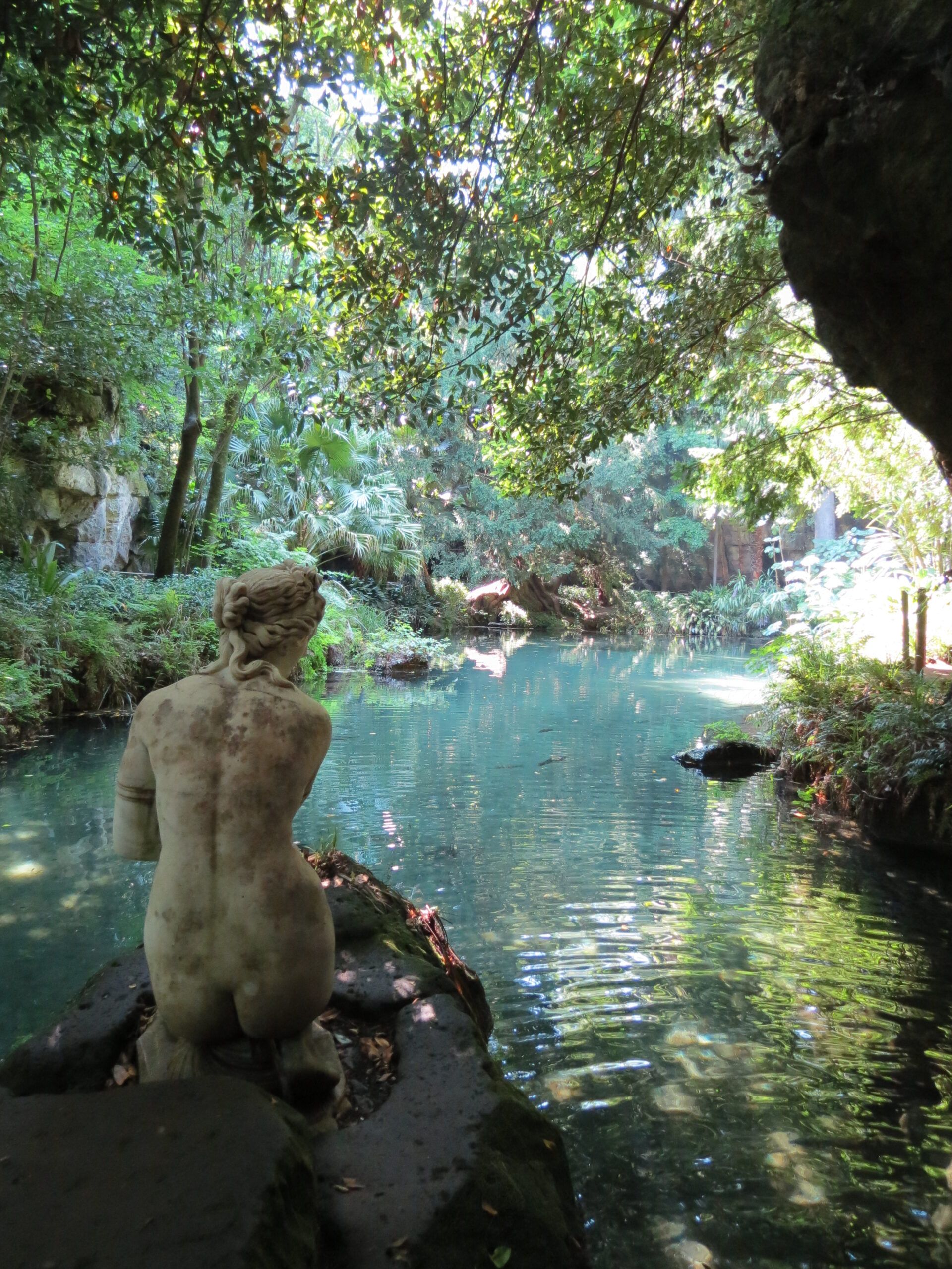 Statue de femme à genou face à une étandue d'eau